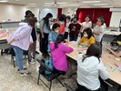 學員們聚集在講座身邊並認真聽其示範紙黏土訣竅